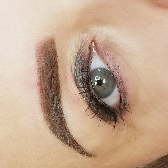 Zbliżenie na oko z makijażem permanentnym brwi; widoczna precyzyjna pigmentacja i podkreślone rzęsy.