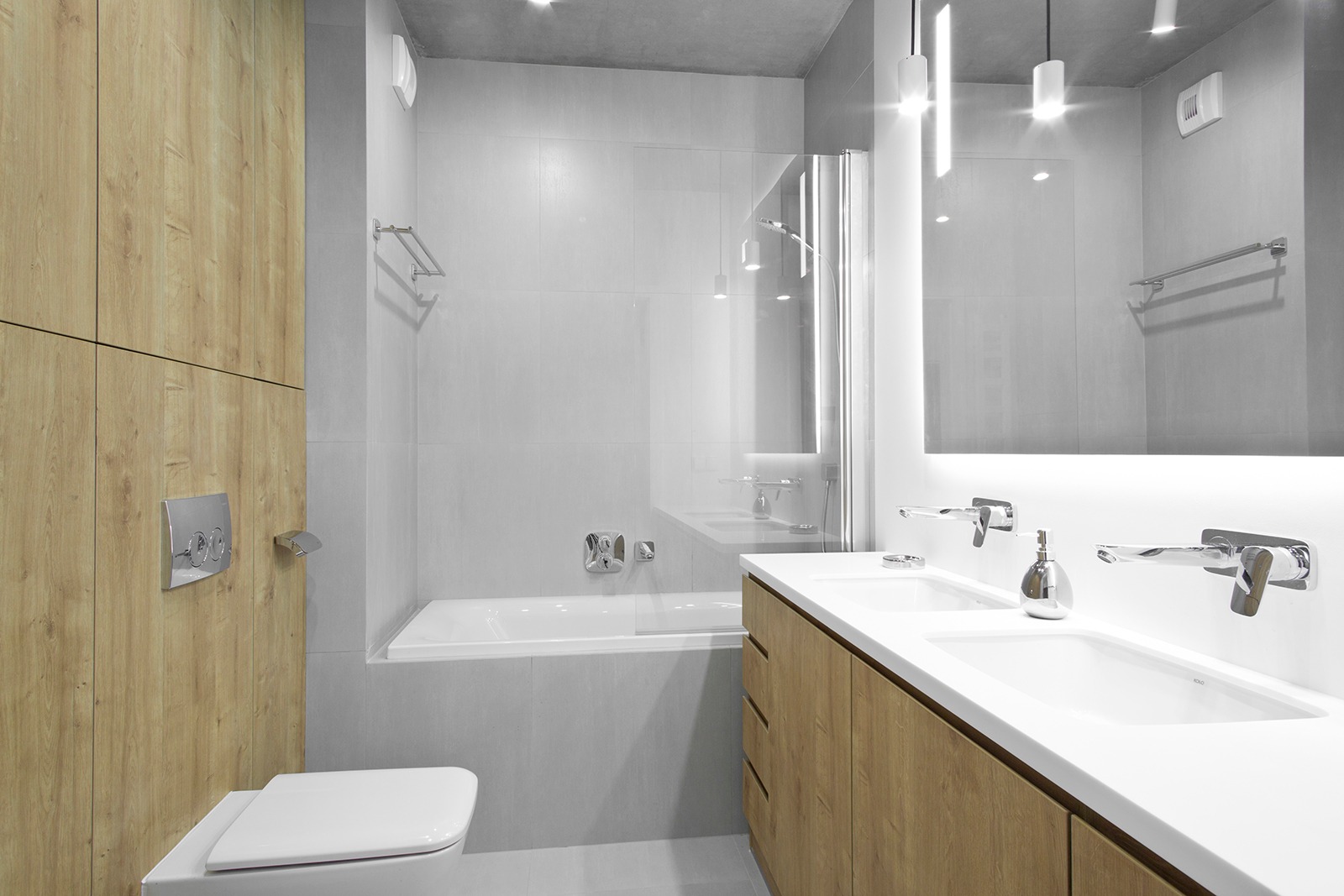 Nowoczesna łazienka z drewnopodobnymi szafkami, podwójną umywalką i podświetlanym lustrem, minimalistyczna armatura.