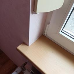 Zaklad ogólnobudowlany Gniewko Surdyk - Fragment pokoju z różową ścianą, jasnym parapetem i grzejnikiem z termostatem, widoczne krople wody na szybie okna.