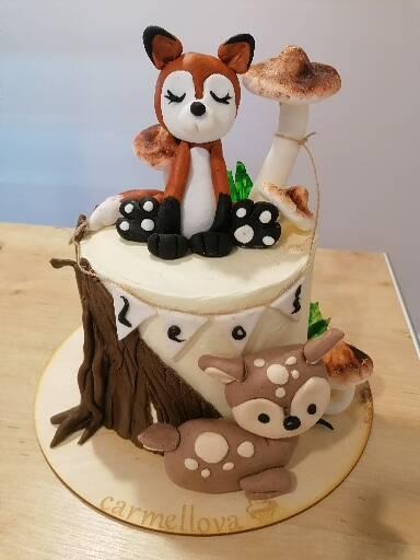 Tort urodzinowy w stylu leśnym z figurkami lisa i sarny z masy cukrowej, dekorowany imitacją pnia drzewa i muchomora.