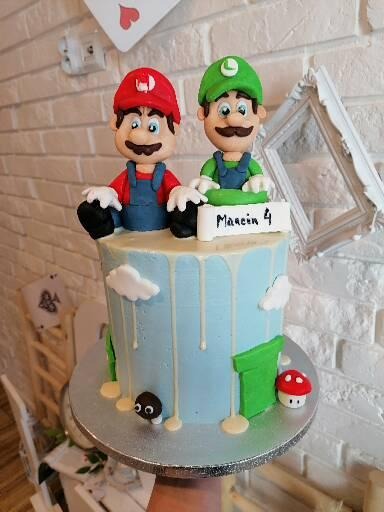 Tort urodzinowy w stylu Mario Bros z figurkami Mario i Luigiego na górze, dekorowany chmurkami, rurami i grzybami, z napisem 'Marcin 4'.