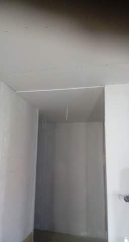 Wnętrze w trakcie remontu: sufit i ściany pokryte płytami gipsowo-kartonowymi, widoczne łączenia i przewody elektryczne.