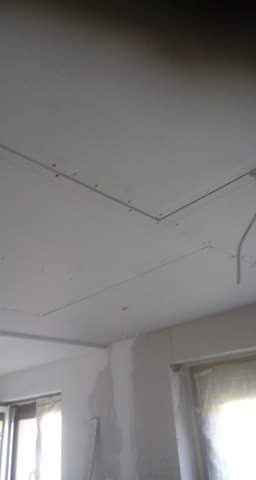 Sufit z zamontowaną konstrukcją metalową pod płyty gipsowo-kartonowe, widoczne łączenia i fragment ściany z zaciekami.