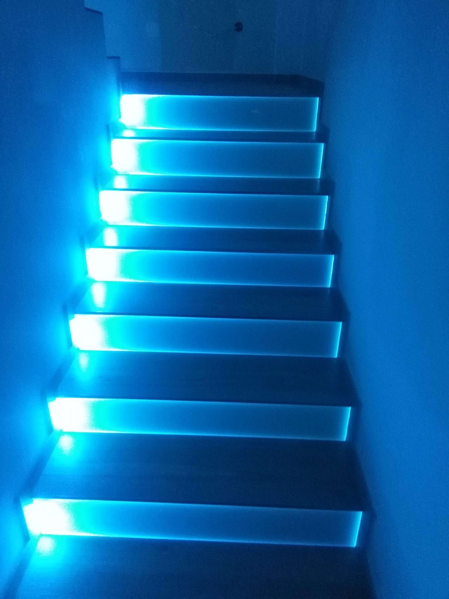 Schody z podświetleniem LED w odcieniach niebieskiego, zamontowane w domu w Starych żdżarach, oświetlające ściany.