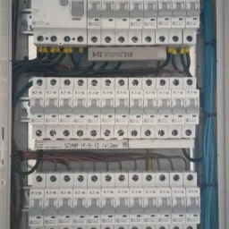 Rozdzielnica elektryczna z zainstalowanymi bezpiecznikami EATON, widoczne przewody w różnych kolorach i szyna prądowa. Element instalacji elektrycznej.