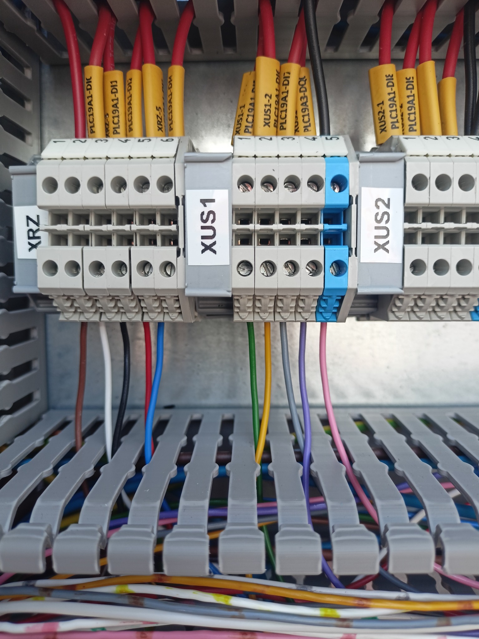 Szczegółowe ujęcie panelu sterowniczego z przewodami oznaczonymi etykietami (XUS1, XUS2, XRZ) i złączkami, ukazujące precyzję instalacji elektrycznej.