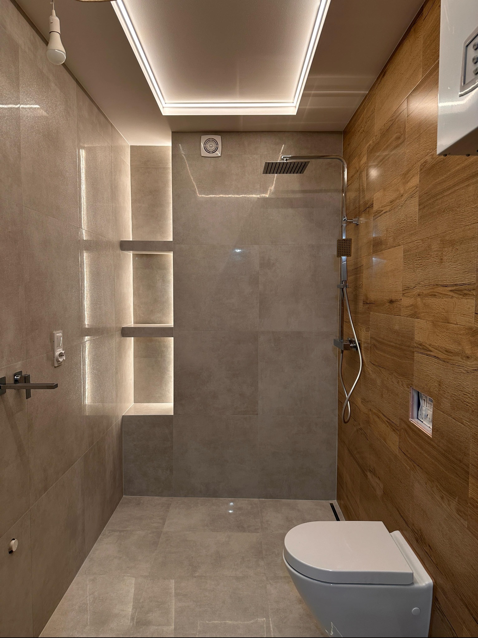 Nowoczesna łazienka z kabiną prysznicową typu walk-in i podświetlanymi półkami w Mściszewicach. Płytki imitujące drewno, minimalistyczna armatura.