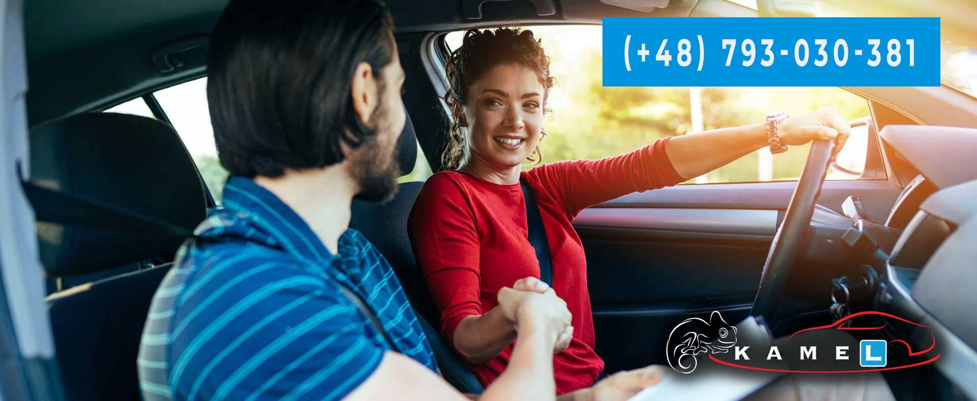 Instruktor z Jastrzębia-Zdroju podaje dłoń kursantce za kierownicą samochodu, uśmiechnięta kobieta w czerwonej bluzce trzyma kierownicę.