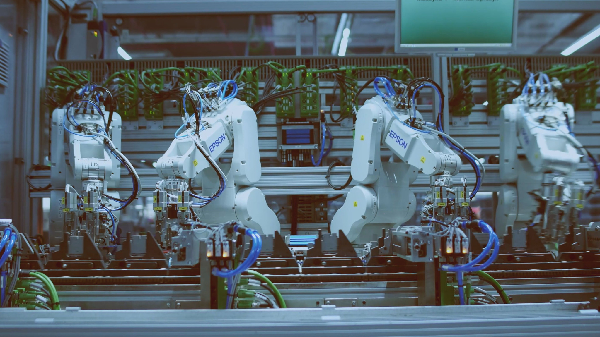 Zautomatyzowana linia produkcyjna z robotami przemysłowymi marki Epson, wykonującymi precyzyjne zadania montażowe w sterylnych warunkach, z widocznymi przewodami i elementami sterującymi.