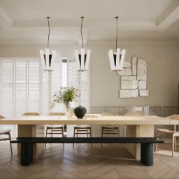 Jasna jadalnia z drewnianym stołem, krzesłami i ławką na parkiecie ułożonym w jodełkę, wiszące lampy z białymi kloszami, abstrakcyjna dekoracja ścienna i szafka z forniru w tle.