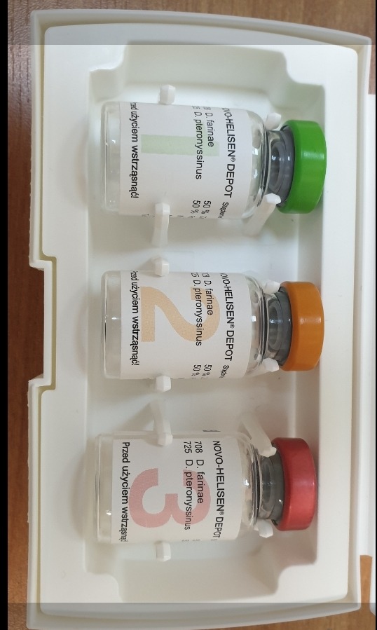 Zestaw trzech fiolek NOVO-HELISEN DEPOT z różnokolorowymi zakrętkami (zielona, pomarańczowa, czerwona) w białym plastikowym opakowaniu, etykiety z informacją o składzie i zaleceniem wstrząśnięcia...