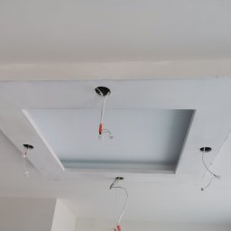 Firma Handlowo Usługowa Maciej Kaliszewski - Biały sufit podwieszany z otworem na oświetlenie, widoczne przewody elektryczne.