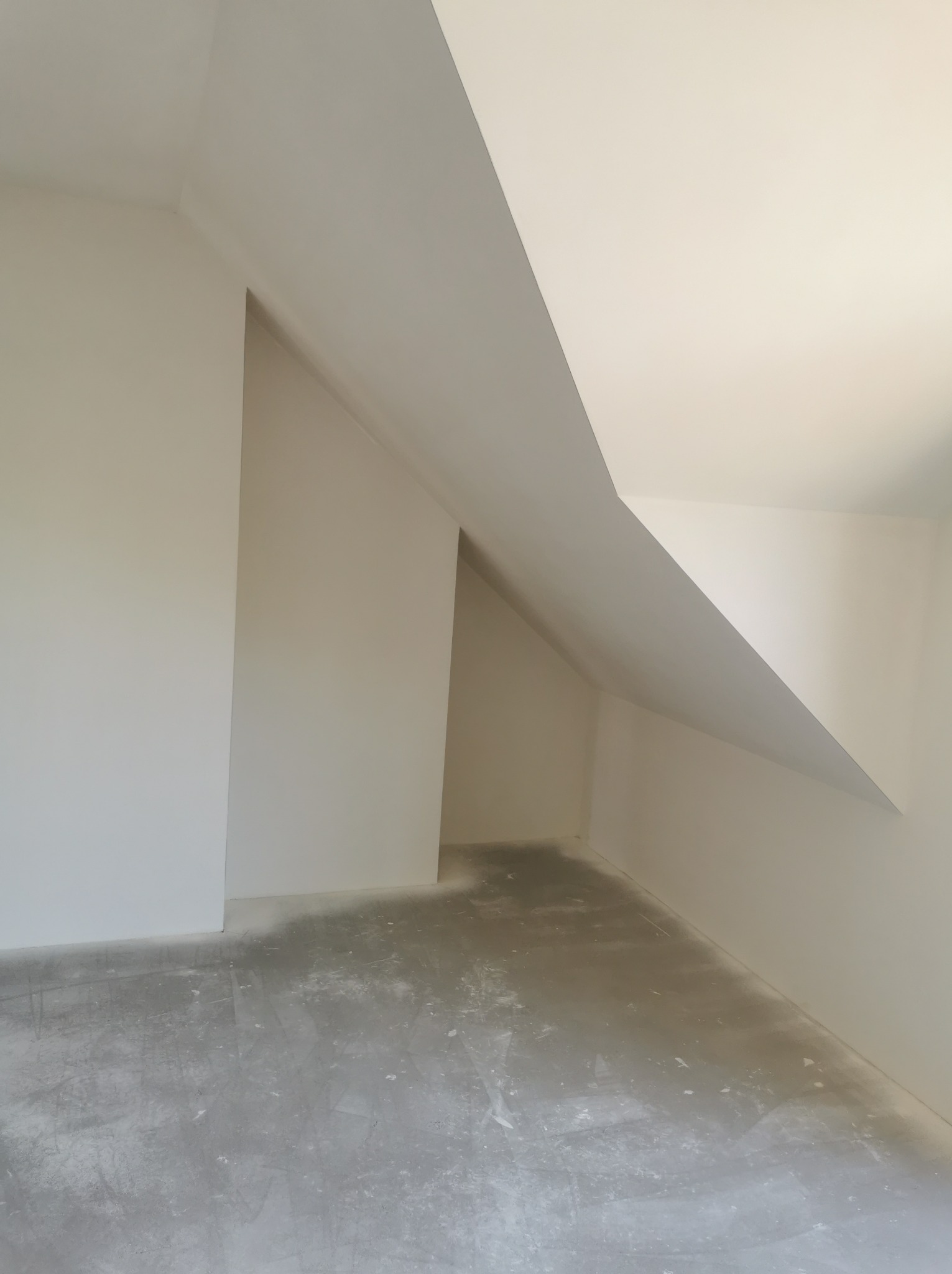 Poddasze po wstępnym wyrównaniu ścian i sufitu, widoczne ślady pyłu na szarej, surowej posadzce.