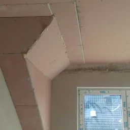 Montaż płyt kartonowo-gipsowych na poddaszu z widocznym oknem VEKA, etap przed szpachlowaniem i malowaniem.