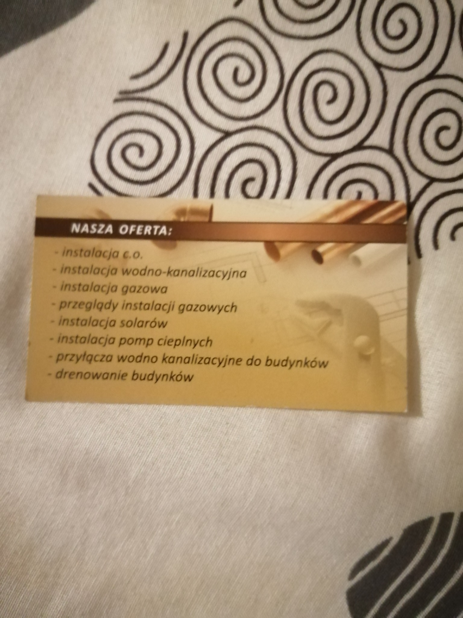 Wizytówka firmy instalacyjnej z napisem 'NASZA OFERTA' i wyliczeniem usług: instalacja c.o., wodno-kanalizacyjna, gazowa, solarna, pomp ciepła, przeglądy instalacji gazowych, przyłącza...