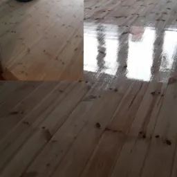 Parkiet z jasnego drewna, częściowo po obróbce szlifierką, z widocznym połyskiem lakieru w oknach odbijających się od podłogi.