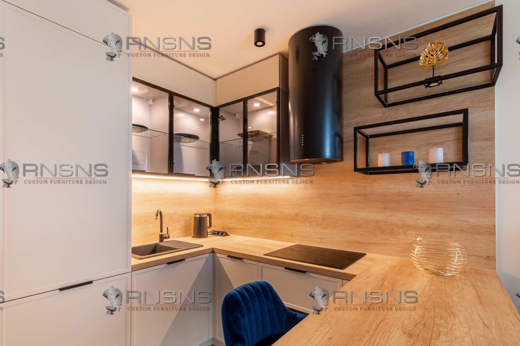 Nowoczesna kuchnia z białymi szafkami, drewnianym blatem, czarnym okapem cylindrycznym, szklanymi szafkami wiszącymi z oświetleniem LED i dekoracyjnymi półkami ściennymi.