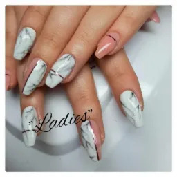 Dłonie z przedłużonymi paznokciami, stylizacja marmurkowa w odcieniach bieli i szarości, akcenty w kolorze pudrowego różu i cienkie, metaliczne paski.