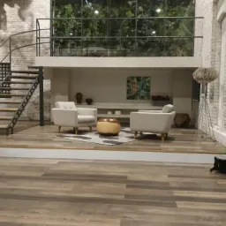 Przestronne wnętrze z antresolą, białymi ceglanymi ścianami, drewnianą podłogą, dwoma fotelami i okrągłym stolikiem kawowym na wzorzystym dywanie.