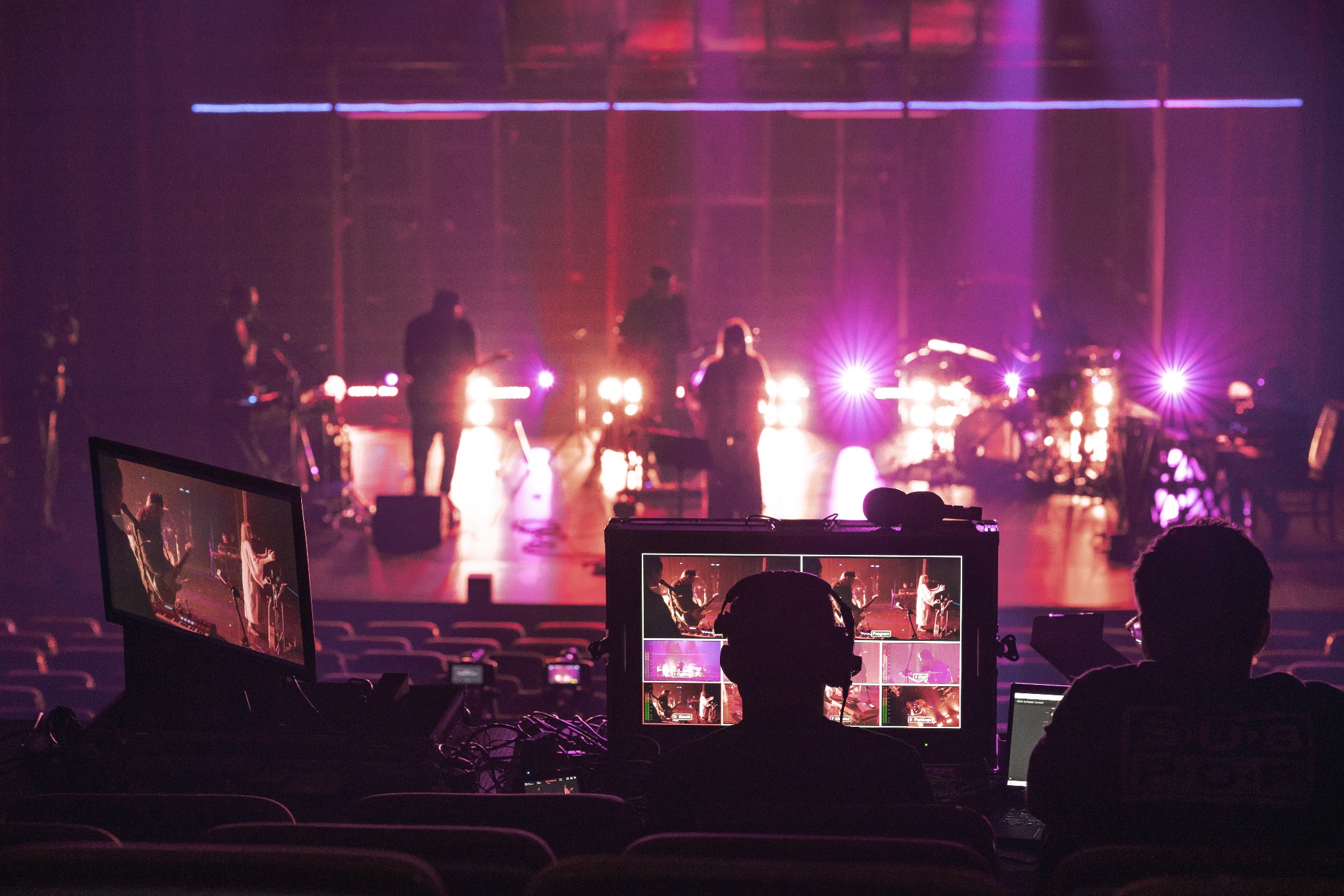 Realizacja nagrania koncertu w Łodzi: operatorzy w słuchawkach monitorują obraz z kamer na scenie, widoczne ekrany z podglądem ujęć.