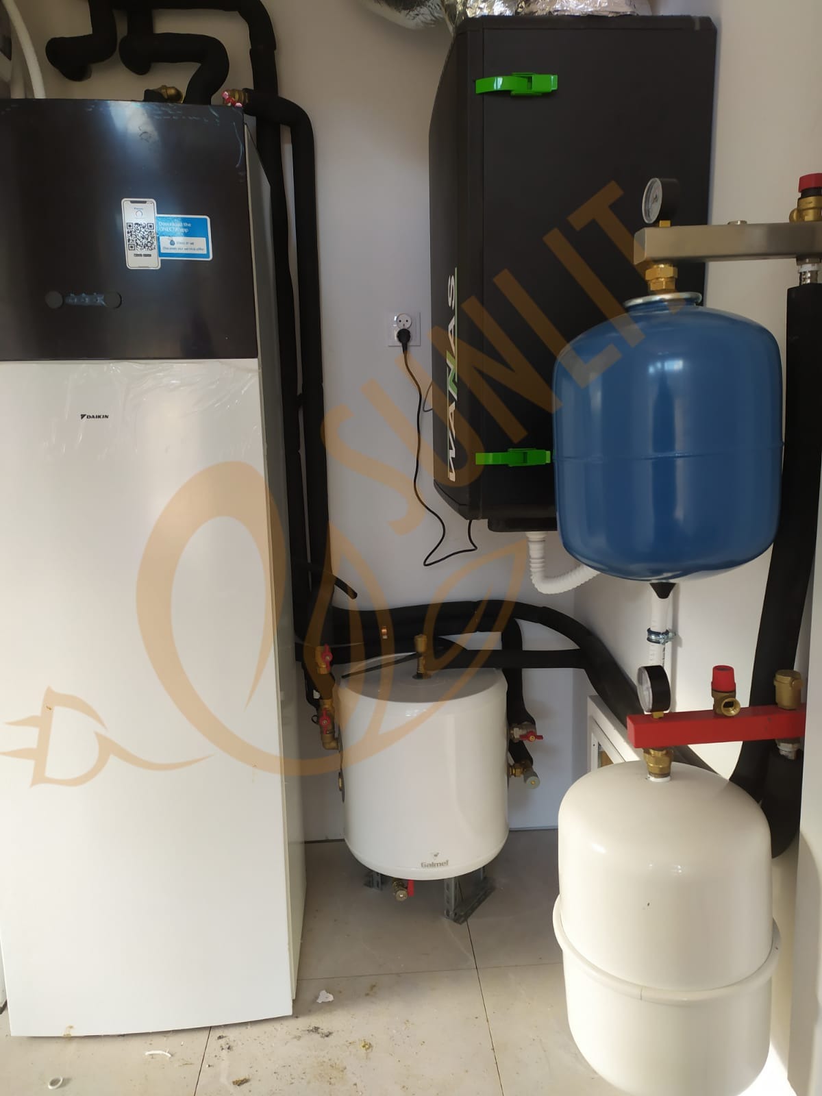 Zestaw urządzeń grzewczych: pompa ciepła Daikin, zasobnik KANVAS i Golmet we Wrocławiu. Czarna izolacja rur, białe ściany, schludna instalacja.