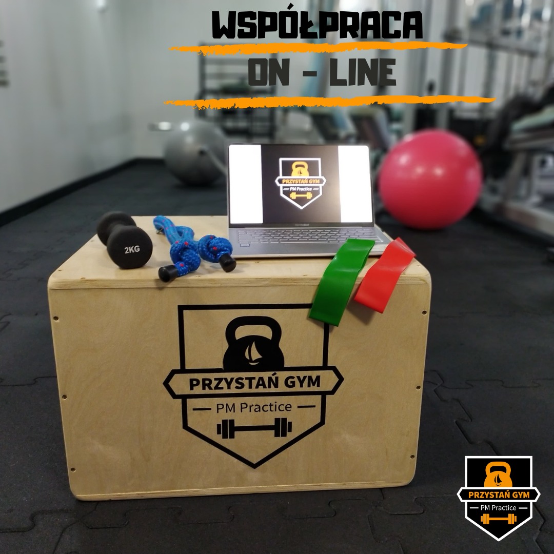 Sprzęt do ćwiczeń online: hantle 2kg, skakanka, laptop z logo siłowni, gumy oporowe, piłka gimnastyczna w tle.