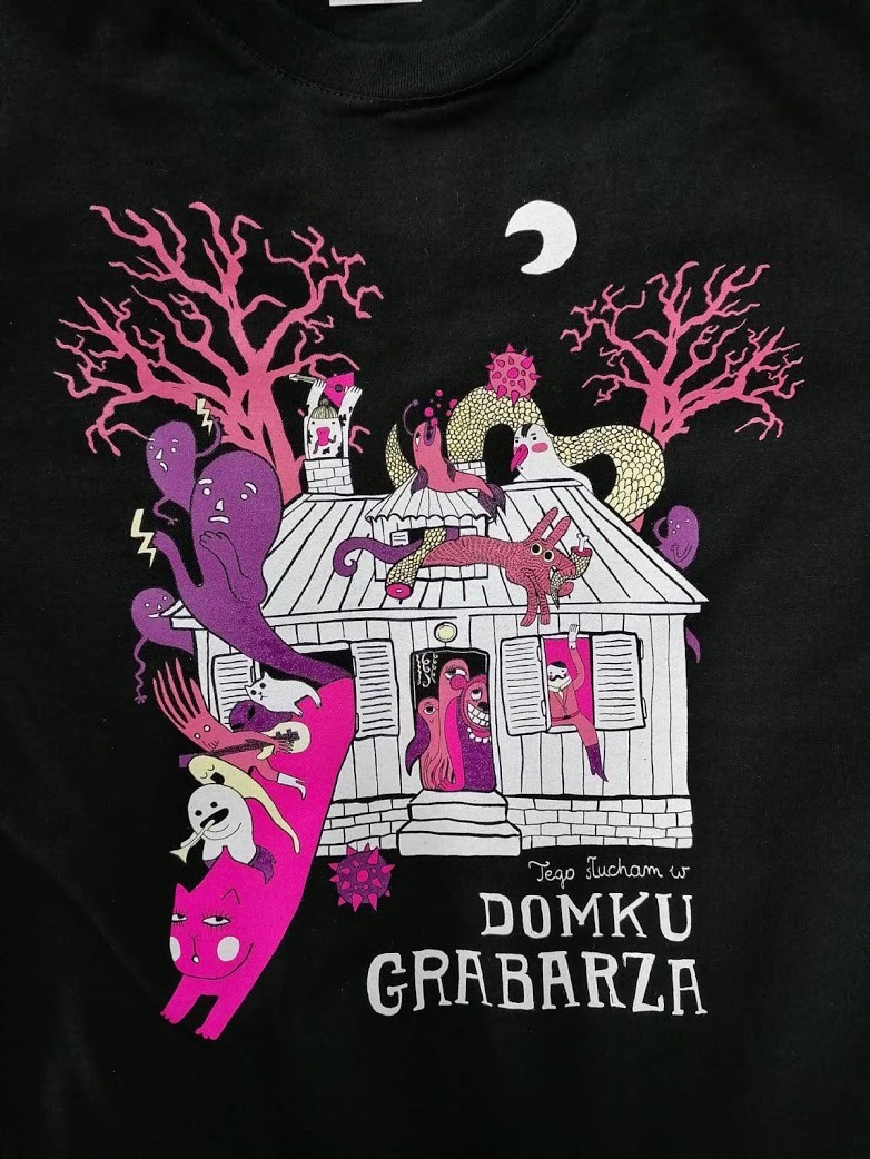 Czarna koszulka z kolorowym, surrealistycznym nadrukiem przedstawiającym dom z duchami, kotem i innymi dziwnymi postaciami w stylu ilustracji książkowej.