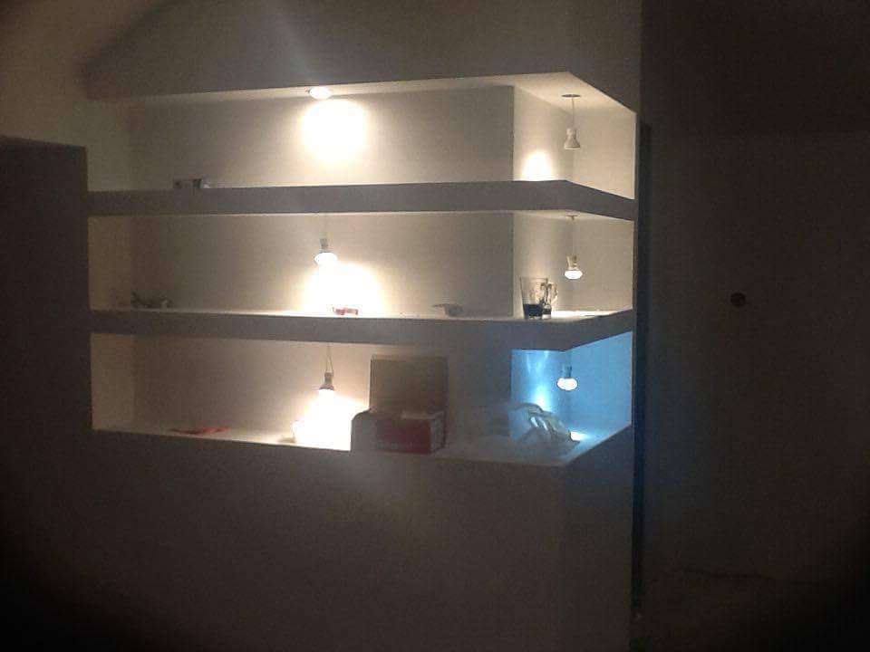 Narożne, podświetlane, wnękowe półki z oświetleniem punktowym w ścianie, z dekoracjami i przedmiotami codziennego użytku