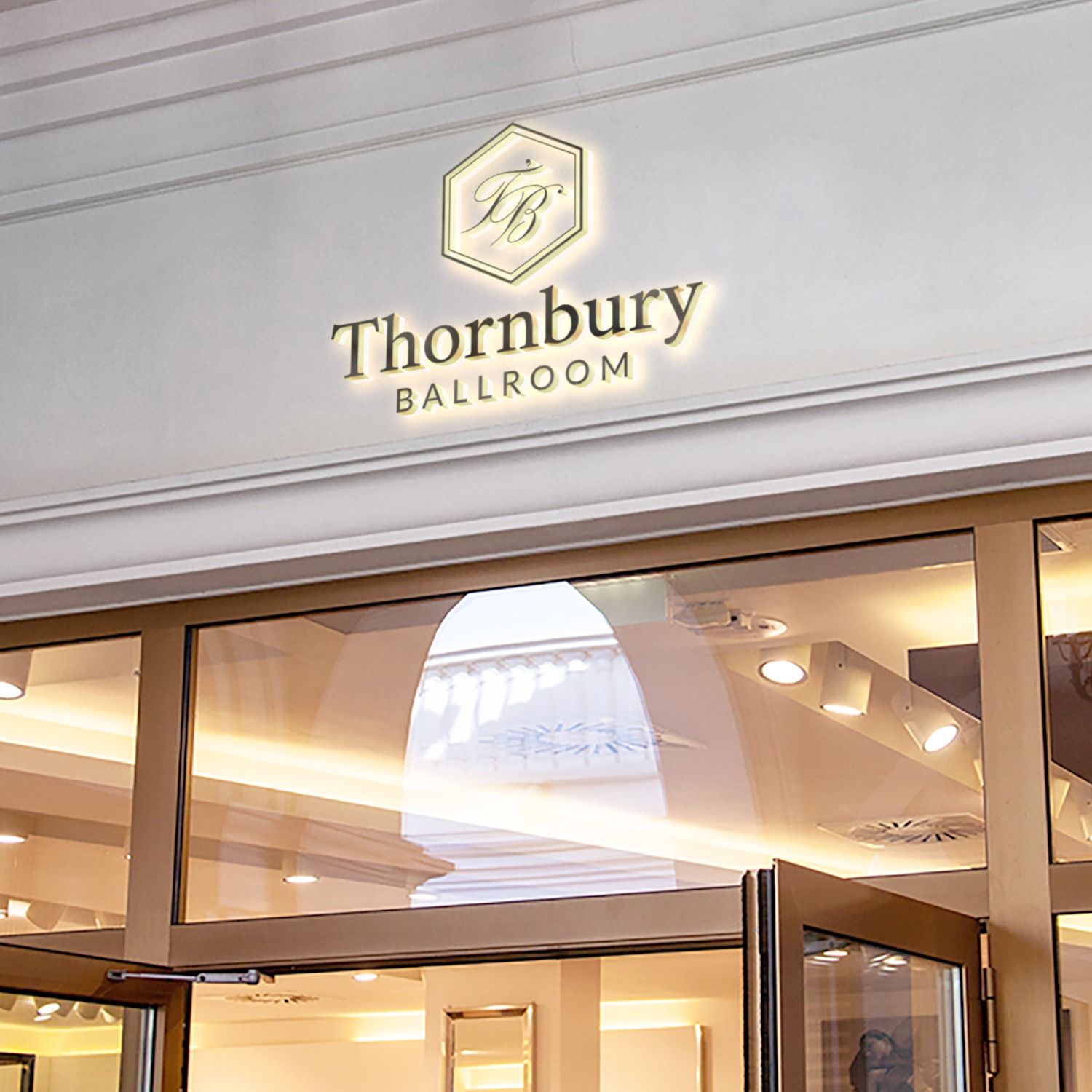 Złote, podświetlane logo Thornbury Ballroom nad wejściem do budynku z przeszklonymi drzwiami.