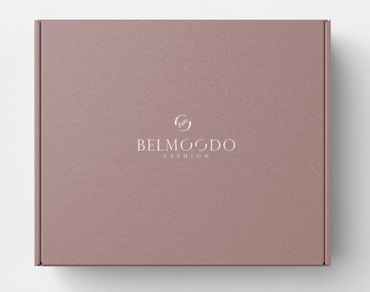 Zamknięte, kwadratowe pudełko w odcieniach różu z minimalistycznym, białym logotypem 'Belmogdo Fashion' pośrodku, ustawione na białym tle.