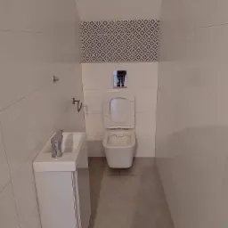 Mała, nowoczesna toaleta z umywalką z szafką, białe płytki ścienne z szarymi fugami ułożone poziomo, dekoracyjny pas płytek nad spłuczką, szara podłoga, otwarte siedzisko toalety.