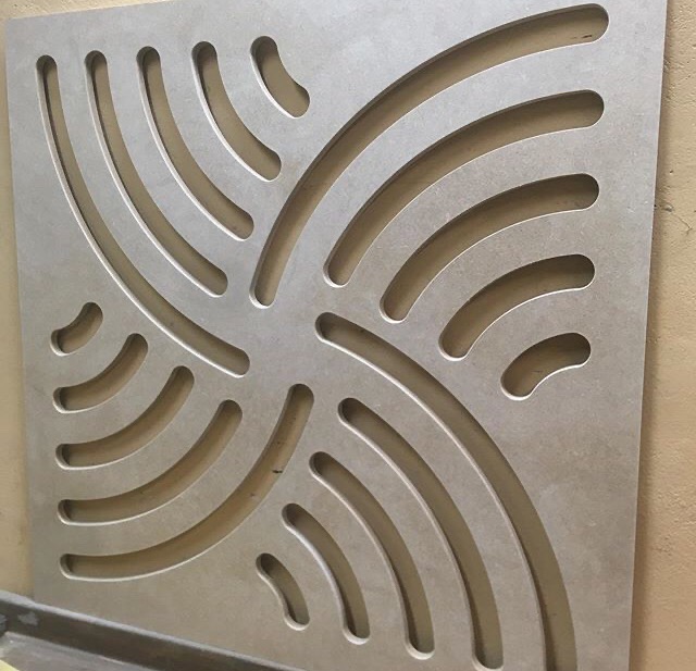 Kwadratowa płyta z wyciętymi, symetrycznie rozmieszczonymi łukami, tworzącymi abstrakcyjny wzór.