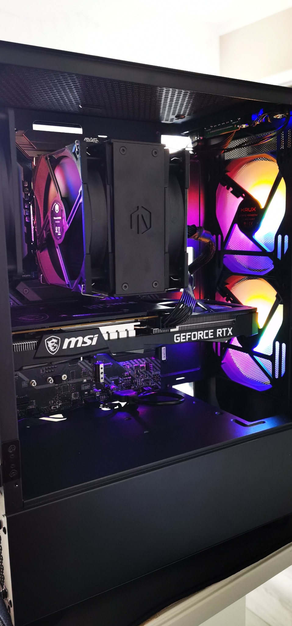 Wnętrze czarnej obudowy komputera stacjonarnego z podświetlanymi wentylatorami RGB, widoczna karta graficzna MSI GeForce RTX i chłodzenie procesora SilentiumPC.