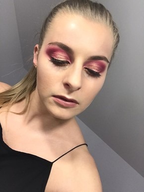 Portret kobiety z intensywnym makijażem oczu w odcieniach różu i złota, z widocznym konturowaniem twarzy i delikatnym podkreśleniem ust, włosy spięte w kucyk.