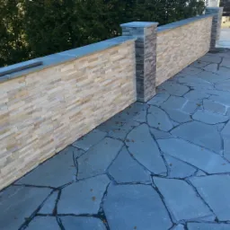 Elewacja zewnętrzna z dekoracyjnej cegły, wykończona szarym kamieniem, z nieregularną kamienną posadzką i opadłymi liśćmi.