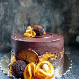 Sweet Kardamoon - Ciemny tort czekoladowy udekorowany kandyzowanymi pomarańczami, kulkami czekoladowymi i kremem na srebrnej podkładce.