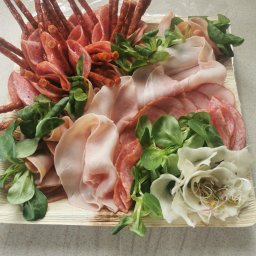 Sweet Kardamoon - Dekoracyjna taca z wędlinami (salami, szynka) i kabanosami, przyozdobiona roszponką i kwiatem z rzodkwi.