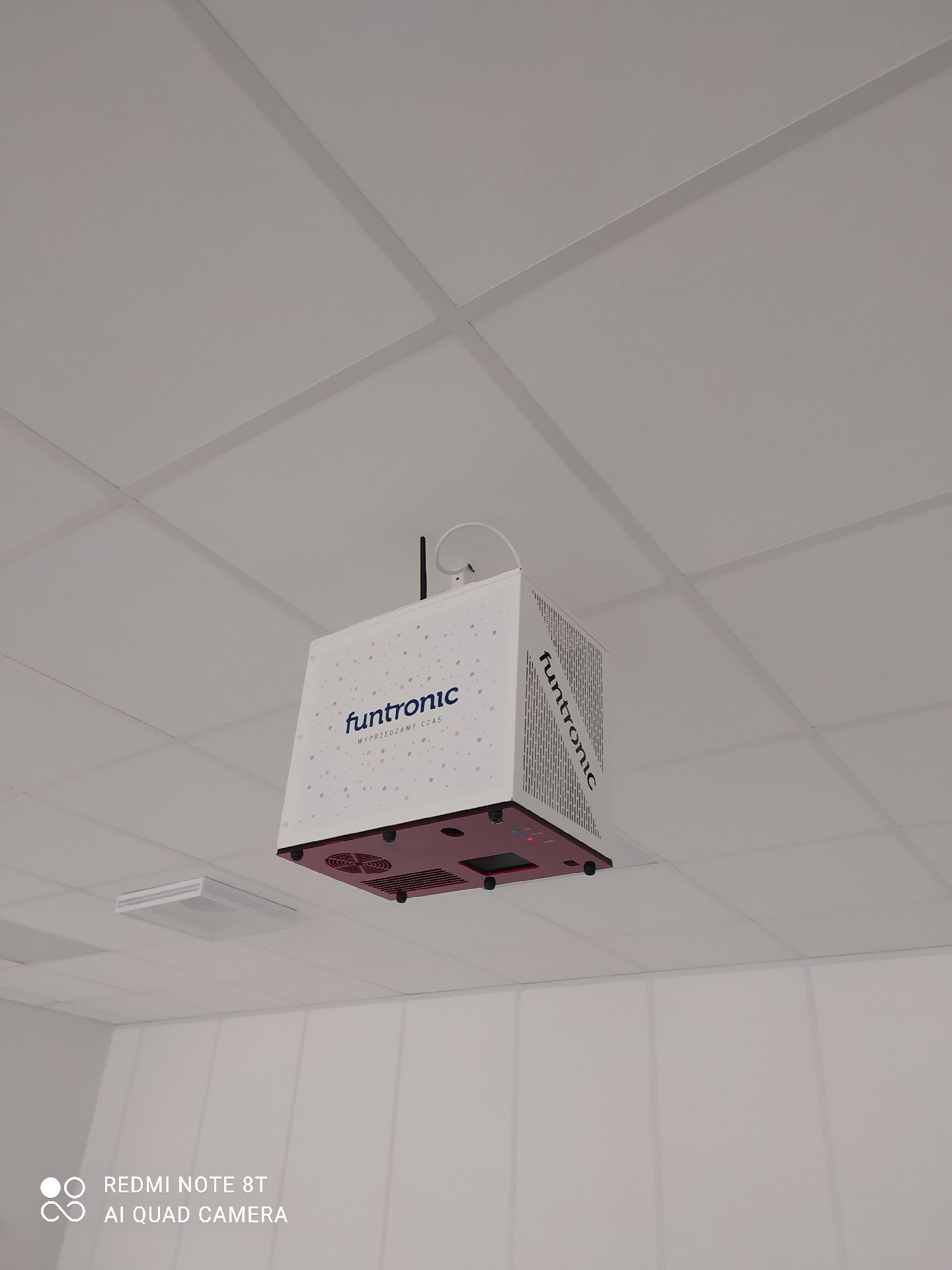 Urządzenie Funtronic zamontowane pod sufitem podwieszanym w biurze, widoczne logo i wentylatory chłodzące.