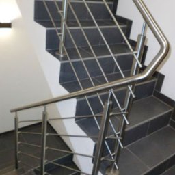 ROB TECH Robert Przewodowski - Wewnętrzne schody z ciemnymi płytkami i nowoczesną balustradą ze stali nierdzewnej, widok z góry, podkreślający minimalistyczny design i precyzję wykonania.