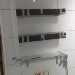 Montaż półek z czarnego marmuru w łazience, przymocowanych taśmą do białych płytek, widoczny stelaż podtynkowy WC i ołówek na metalowym profilu.