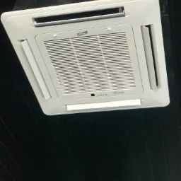 Biała, sufitowa klimatyzacja kasetonowa marki Winia, z widocznymi diodami kontrolnymi, zamontowana na czarnym suficie.