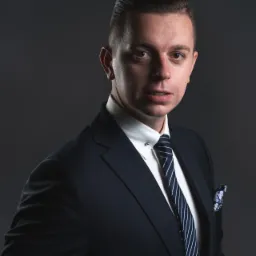 Portret mężczyzny w ciemnym garniturze, białej koszuli z przypinką, i granatowym krawacie w białe paski, z poszetką w kwiatowy wzór, na ciemnoszarym tle.