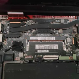 Wnętrze otwartego laptopa Lenovo z widoczną płytą główną, elementami chłodzenia, pamięcią RAM i baterią, podczas naprawy lub modernizacji.