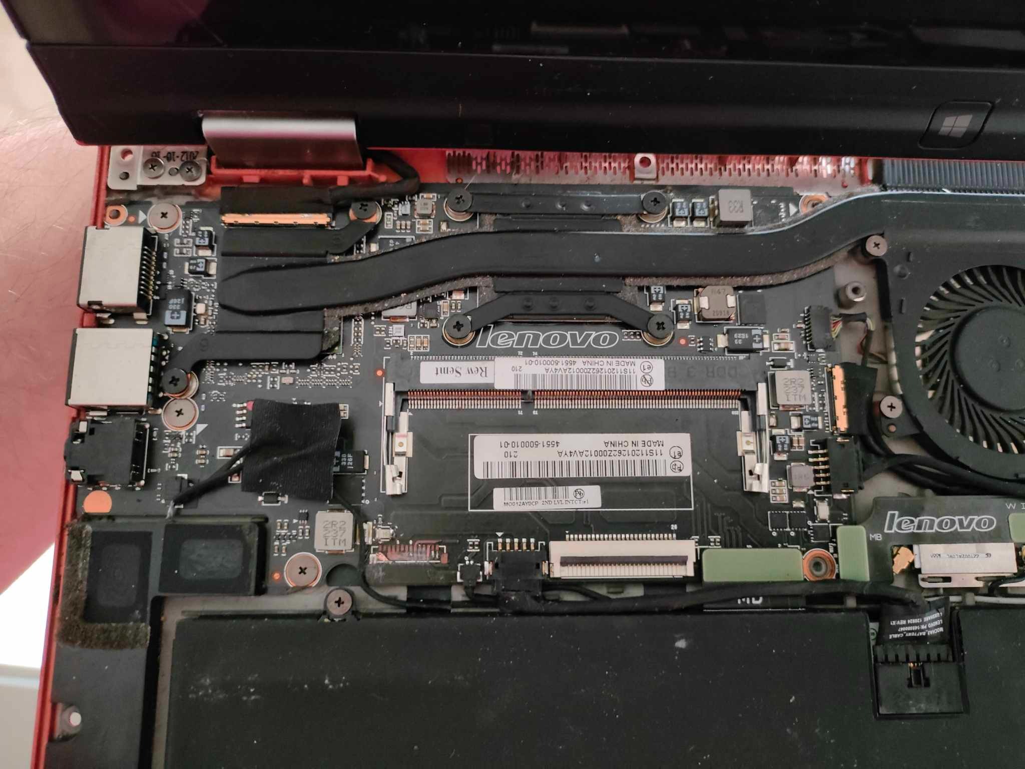 Wnętrze otwartego laptopa Lenovo z widoczną płytą główną, elementami chłodzenia, pamięcią RAM i baterią, podczas naprawy lub modernizacji.