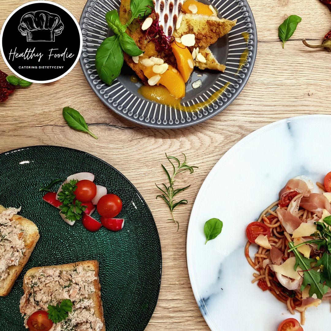 Kompozycja trzech dań na talerzach: grzanki z pastą, smażony chleb z brzoskwiniami i migdałami, oraz spaghetti z szynką parmeńską i pomidorkami koktajlowymi, całość na drewnianym stole z logo firmy...