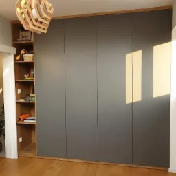 Szara szafa wnękowa z drewnianymi akcentami i otwartą półką z dekoracjami, oświetlona geometryczną lampą wiszącą, na tle drewnianej podłogi.