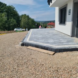 HKS- INFRASTRUKTURA Sławomir Hebda - Nowoczesny taras z szarej kostki brukowej, obrzeża z ciemnej kostki. Widok na dom z numerem 11A i częściowo przygotowany teren pod dalsze prace.