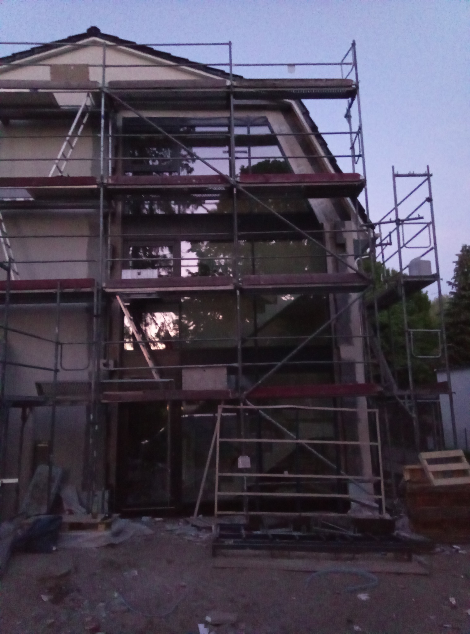 Dom w trakcie montażu stolarki okiennej, widoczne rusztowania i przygotowane otwory okienne.