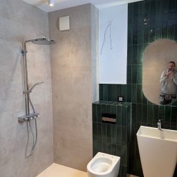 Dawid Filip Filip construction - Nowoczesna łazienka z kabiną prysznicową typu walk-in, umywalką wolnostojącą i toaletą podwieszaną. Ciemnozielone płytki kontrastują z beżowymi ścianami. Widoczne niedokończone prace.