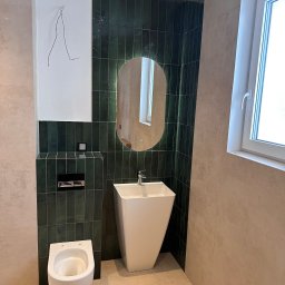 Dawid Filip Filip construction - Nowoczesna łazienka z zielonymi, pionowo ułożonymi płytkami, białą umywalką wolnostojącą i podświetlanym lustrem. Widoczne beżowe płytki na podłodze i ścianach.
